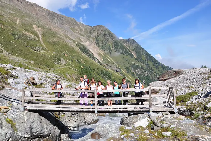 Wanderer auf einer Brücke über einen Gebirgsbach im Sommer