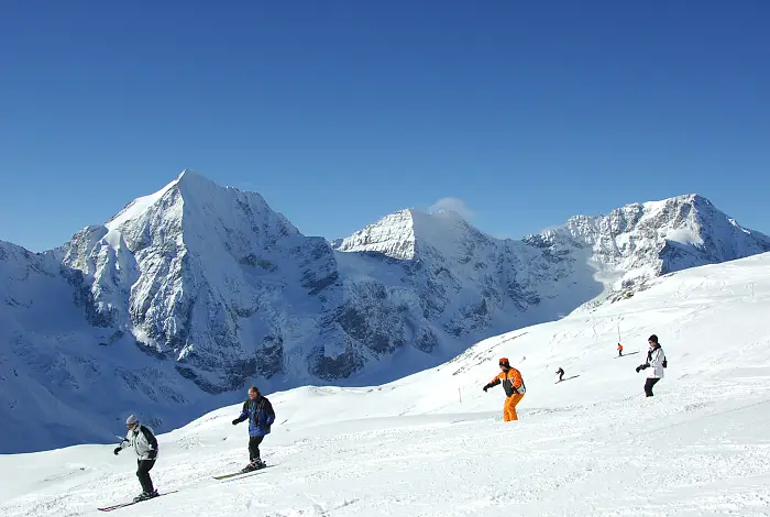 Skifahrer auf einer Piste mit Blick auf die verschneite Bergkette